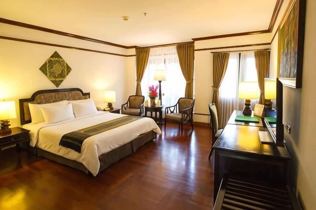 Ein Hotelzimmer mit einem Bett, zwei Stühlen, einem Schreibtisch und einer Lampe.