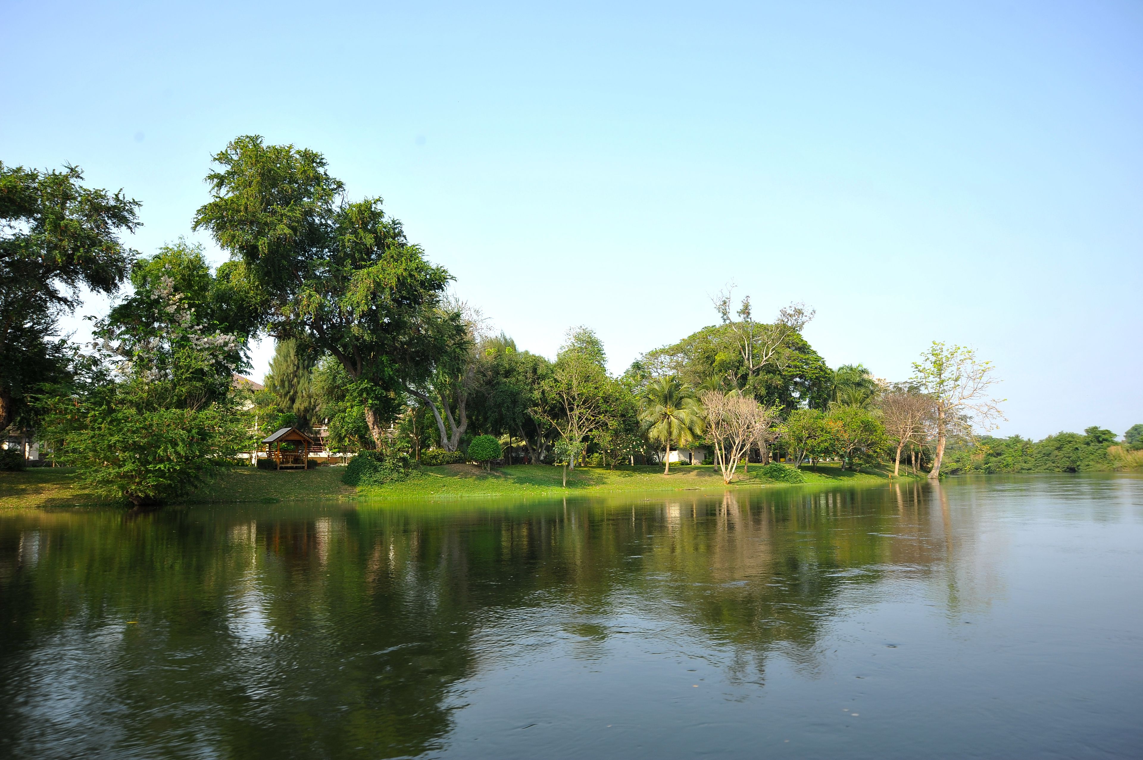 A calm lake with trees and a small wooden structure on the shore.