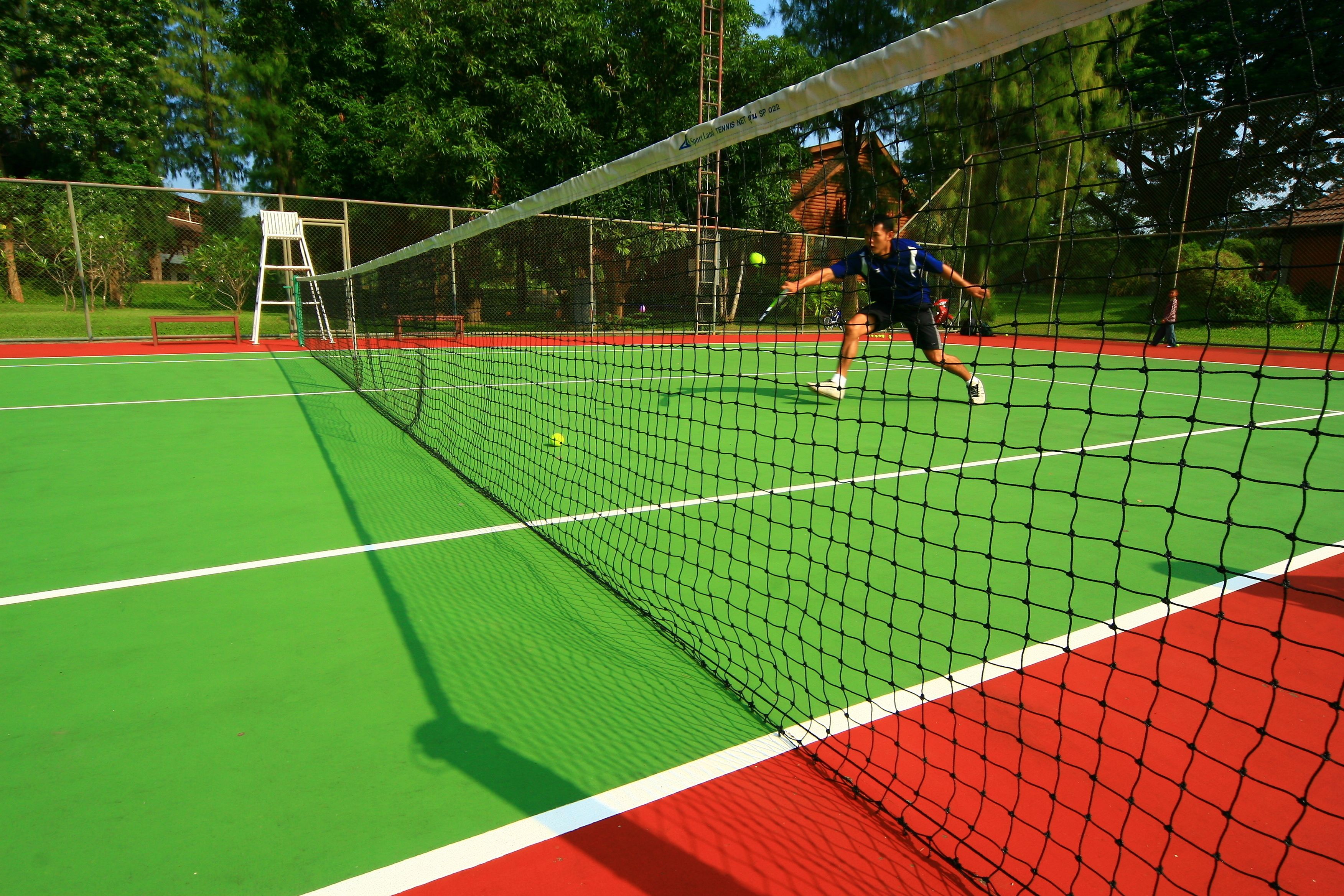 Un court de tennis avec un filet, un banc et une échelle.