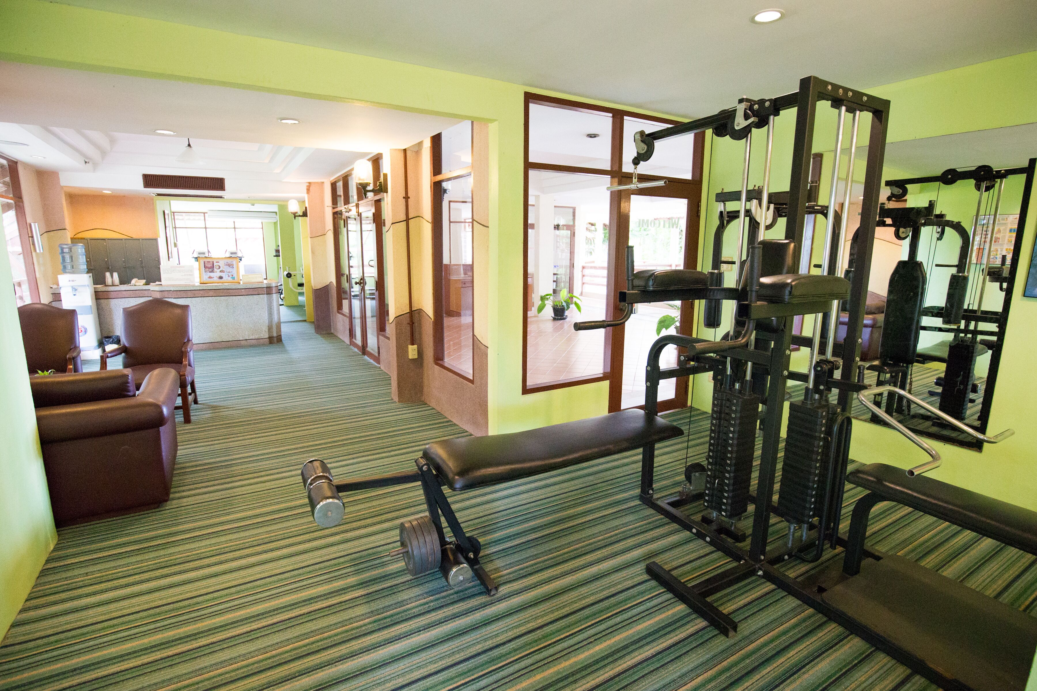 Une salle de sport équipée de matériel d’exercice, un comptoir d’accueil et un espace détente avec des chaises.