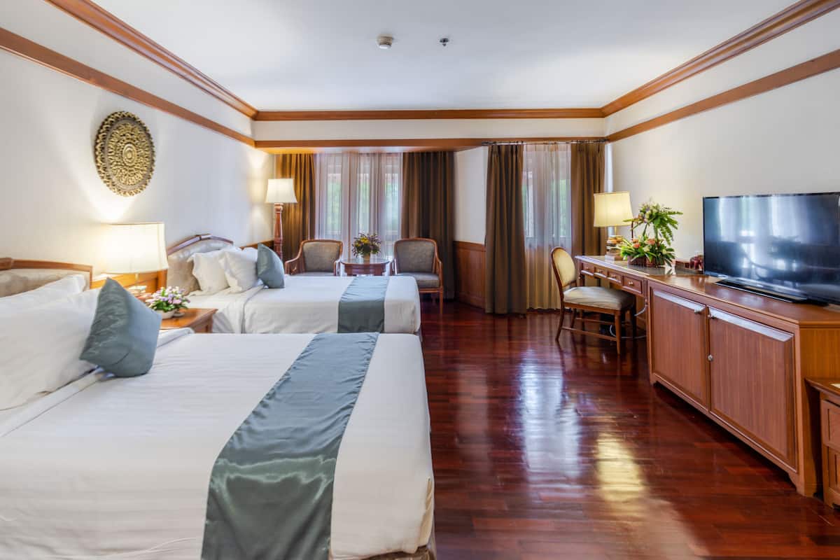 Ein Hotelzimmer mit zwei Betten, einem Fernseher, einem Schreibtisch und einem Stuhl.