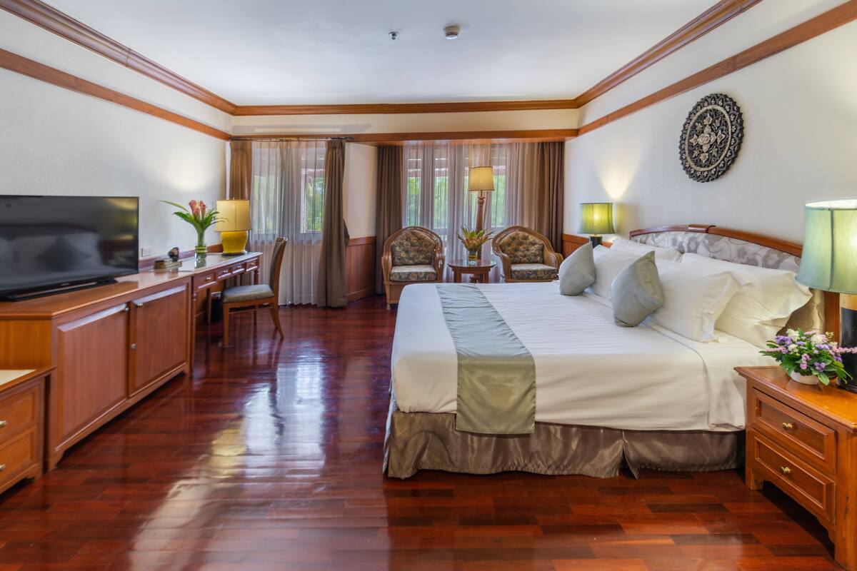 Ein Hotelzimmer mit einem großen Bett, Holzmöbeln, einem Fernseher und einem Schreibtisch mit einer Lampe.