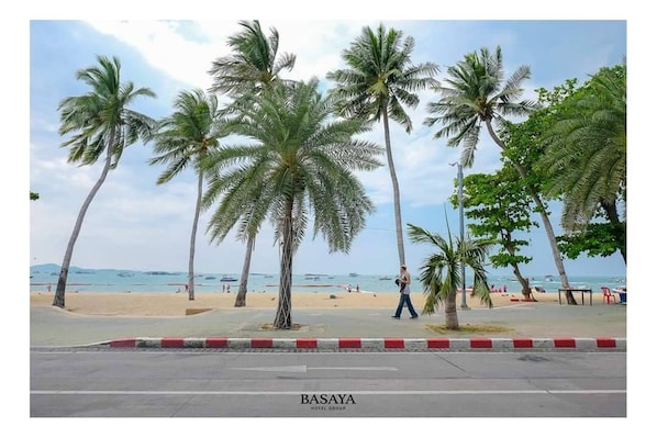 Uma praia com palmeiras e uma pessoa caminhando.