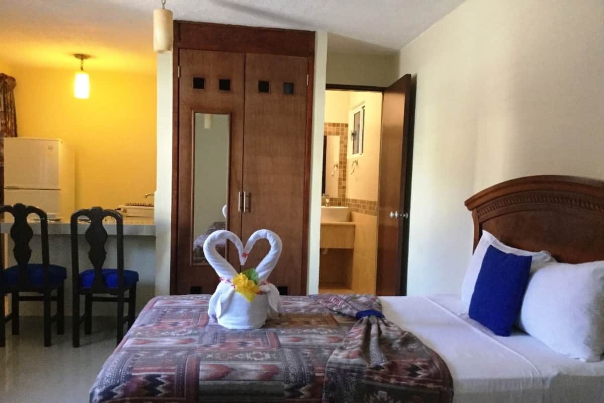 Habitación de hotel con cama, escritorio y baño visible a través de una puerta abierta.
