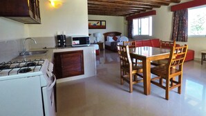 A kitchen with a gas stove, microwave, and sink. There is a dining area with a wooden table and chairs.