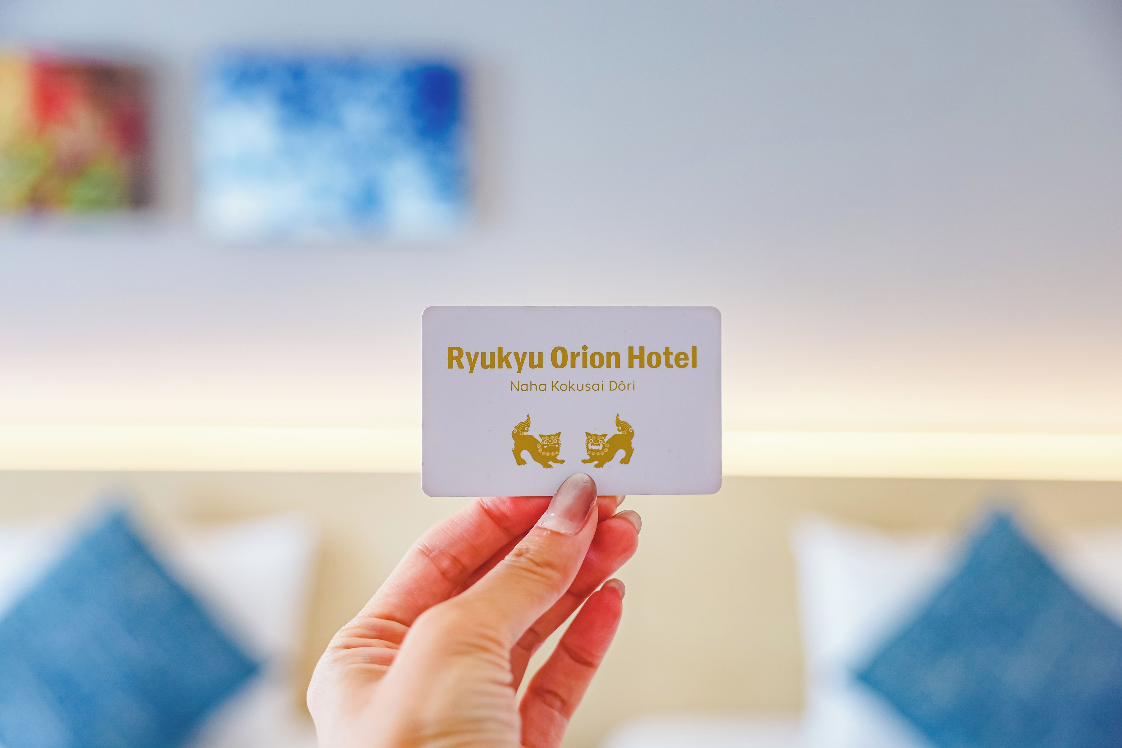 Una mano sostiene una tarjeta de presentación del Hotel Ryukyu Orion.