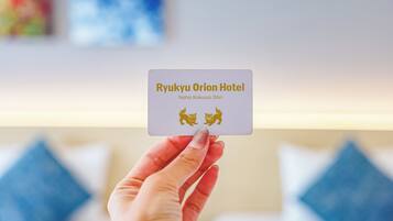 Una mano sostiene una tarjeta de presentación del Hotel Ryukyu Orion.