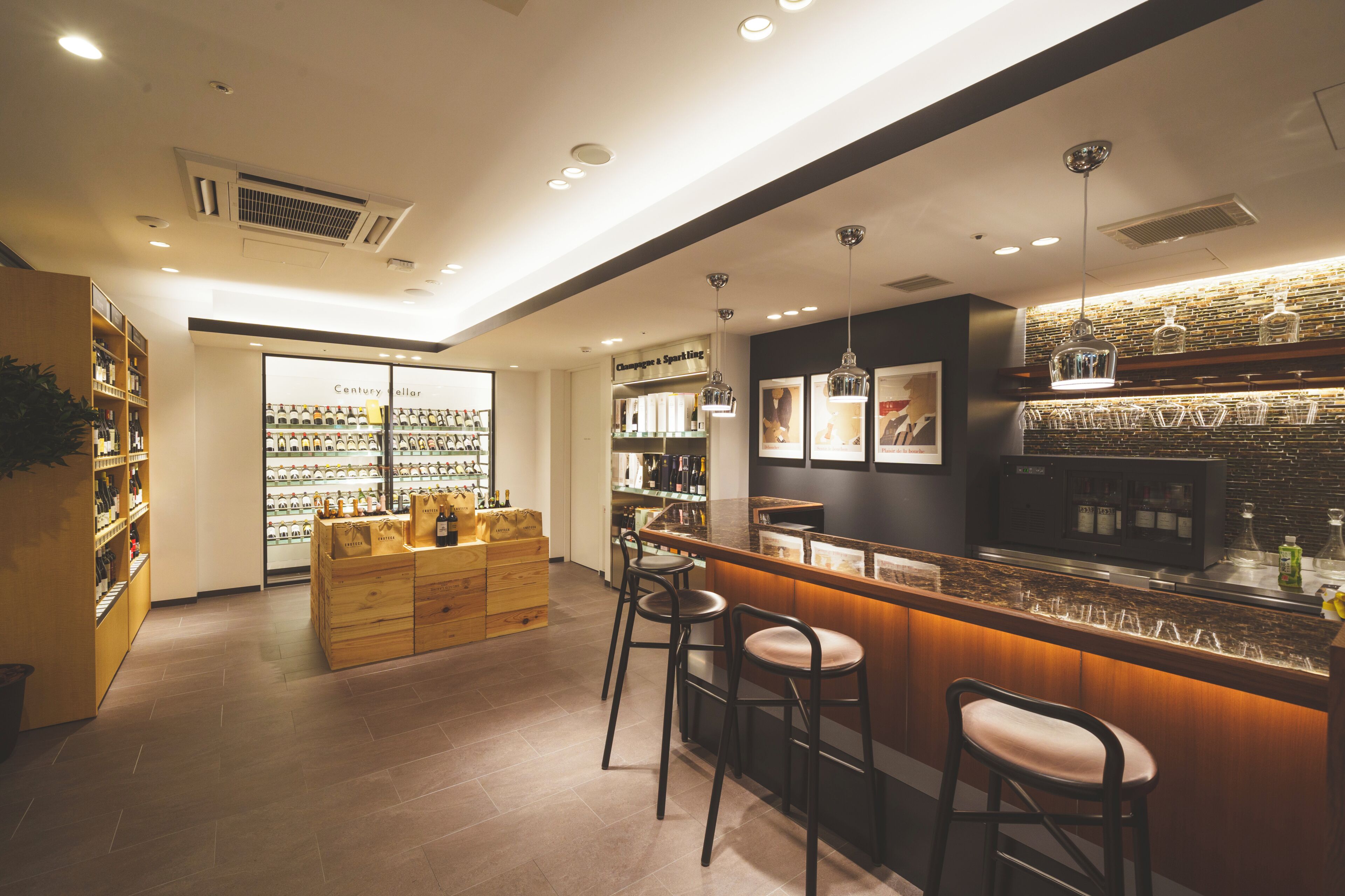 A modern bar area with stools, a counter, and shelves stocked with bottles.