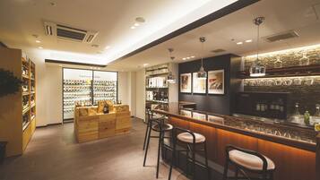 A modern bar area with stools, a counter, and shelves stocked with bottles.