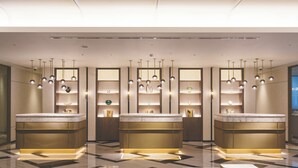 A modern lobby with three reception desks, pendant lighting, and a geometric floor pattern.
