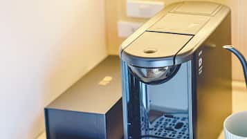 Una cafetera con una bandeja de goteo, una caja y una taza sobre una mesa.