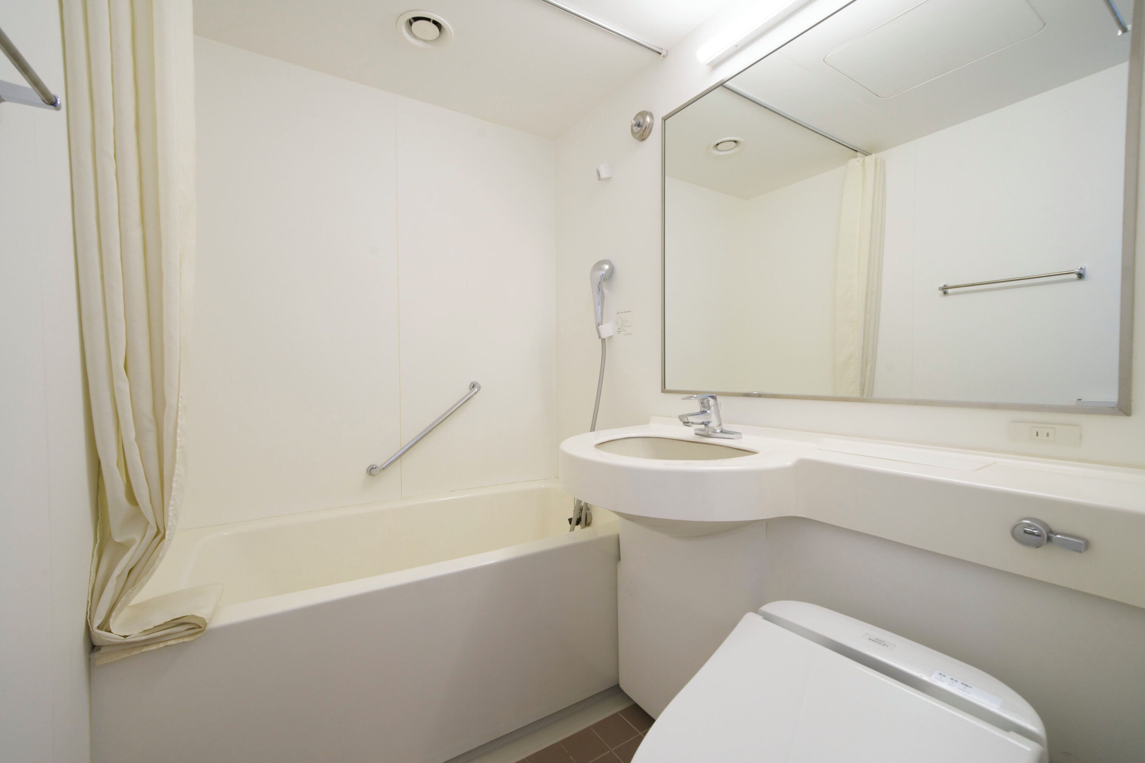 A bathroom with a bathtub, a sink, a toilet, and a mirror.