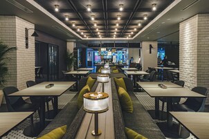 Un interior de restaurante moderno con techos altos, varias zonas de estar y una barra central.