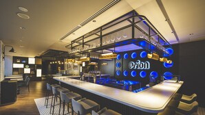 A modern bar area with a long counter, bar stools, and a neon sign. - Ryukyu Orion Hotel Naha Kokusai Dori (Naha)