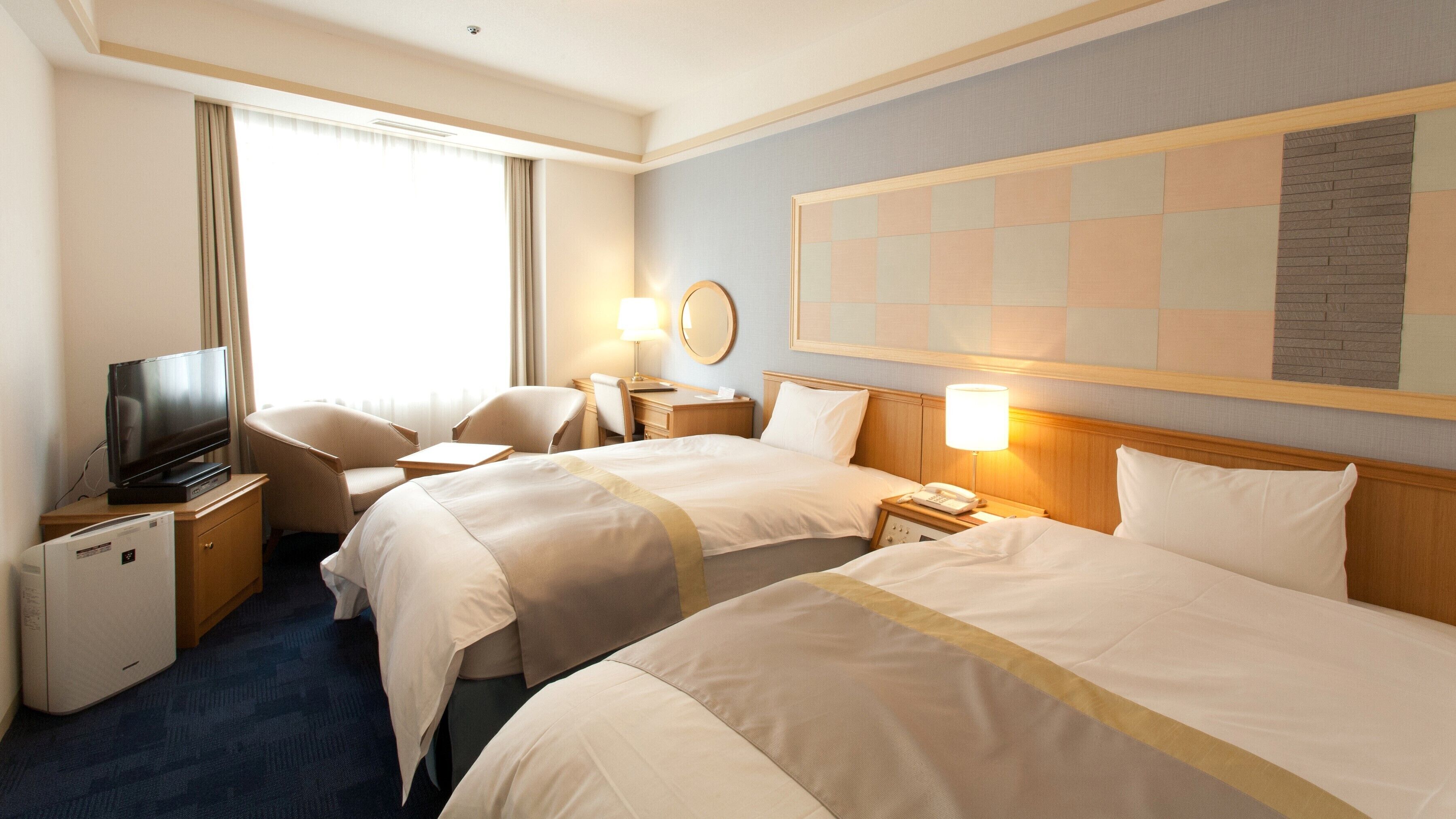 A hotel room with two beds, a television, a desk, and a chair.
