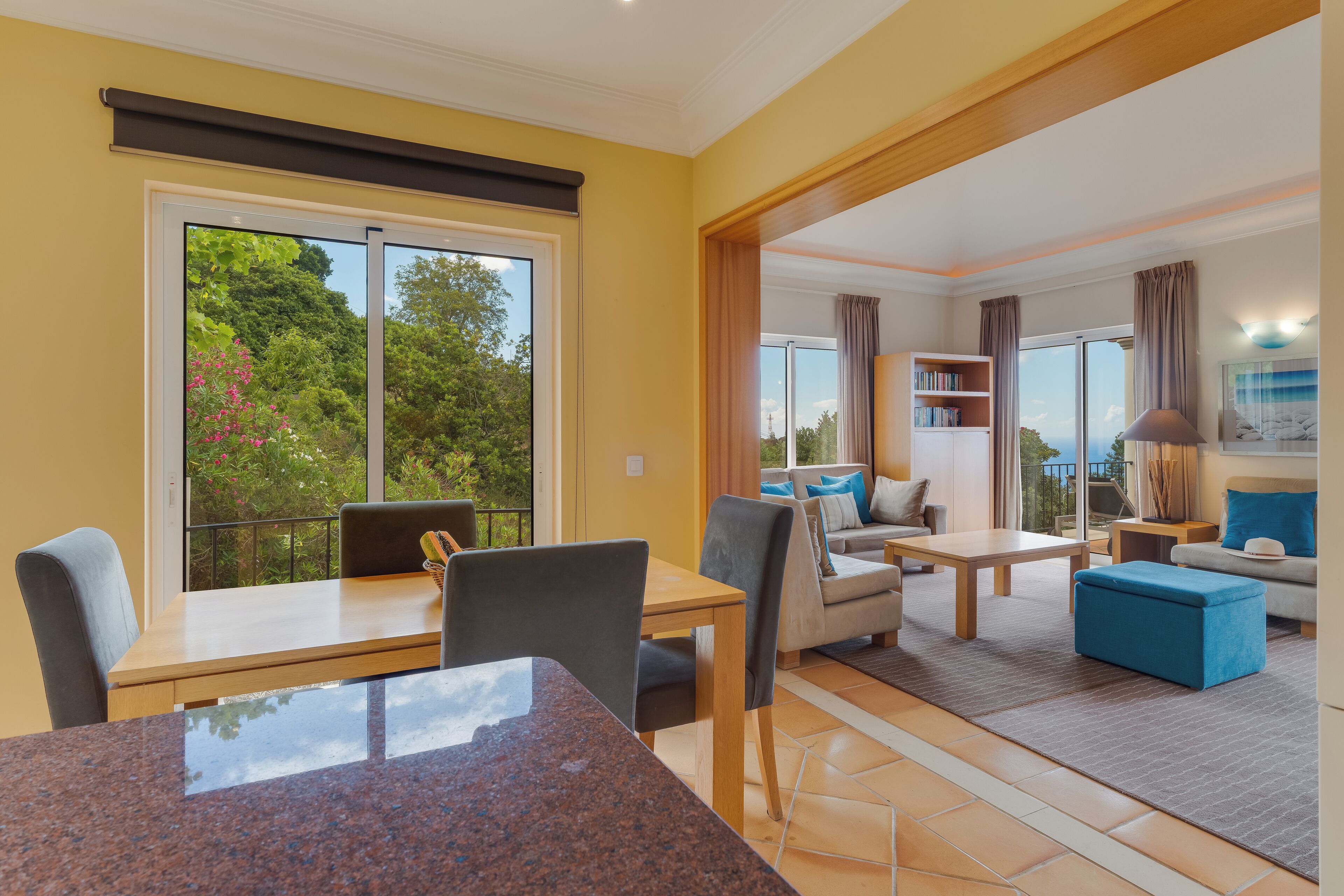 Een moderne woonkamer met een eethoek, grote ramen en een balkon.