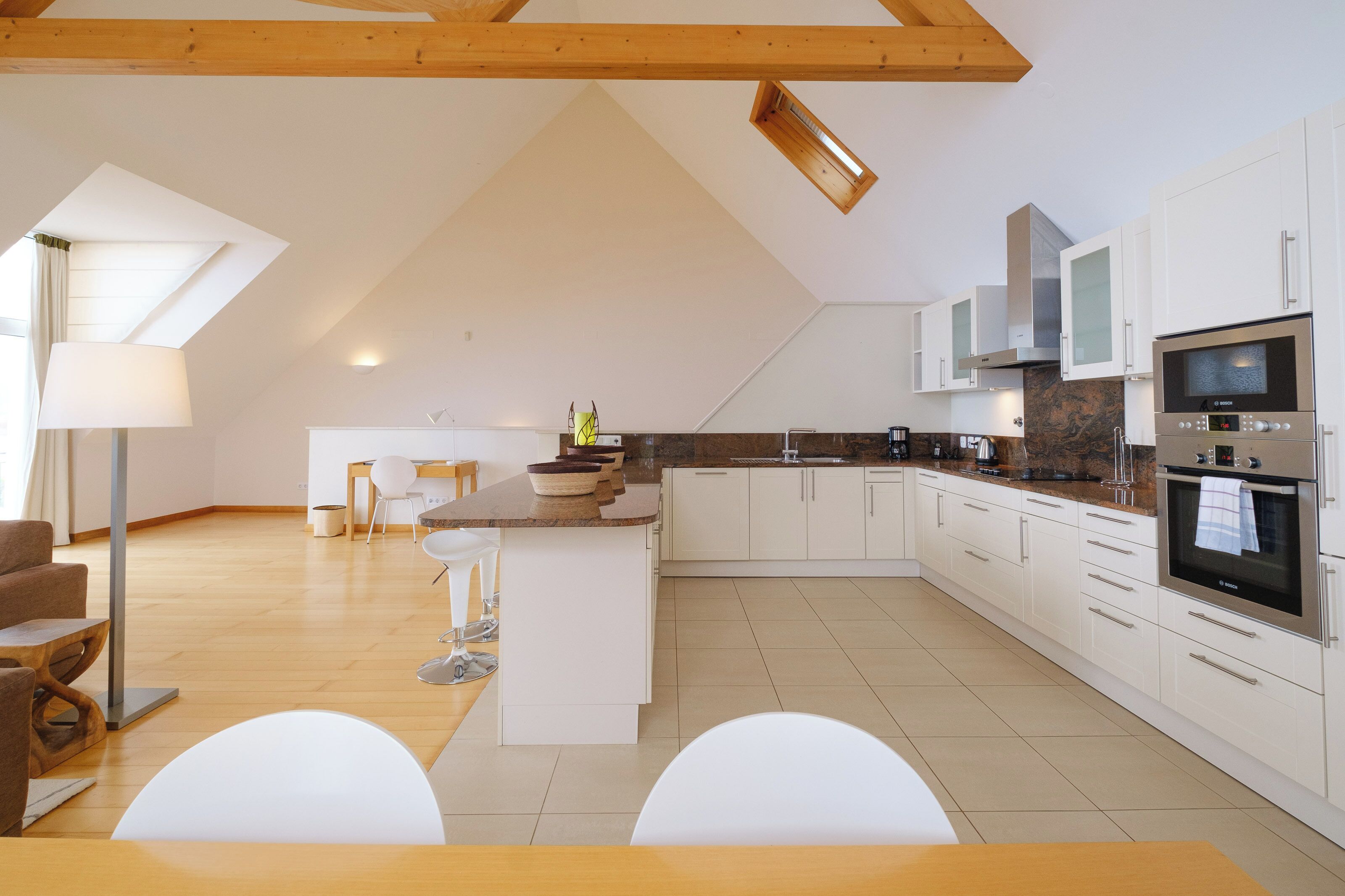 Een ruime keuken met witte kastjes, een centraal eiland en moderne apparatuur.