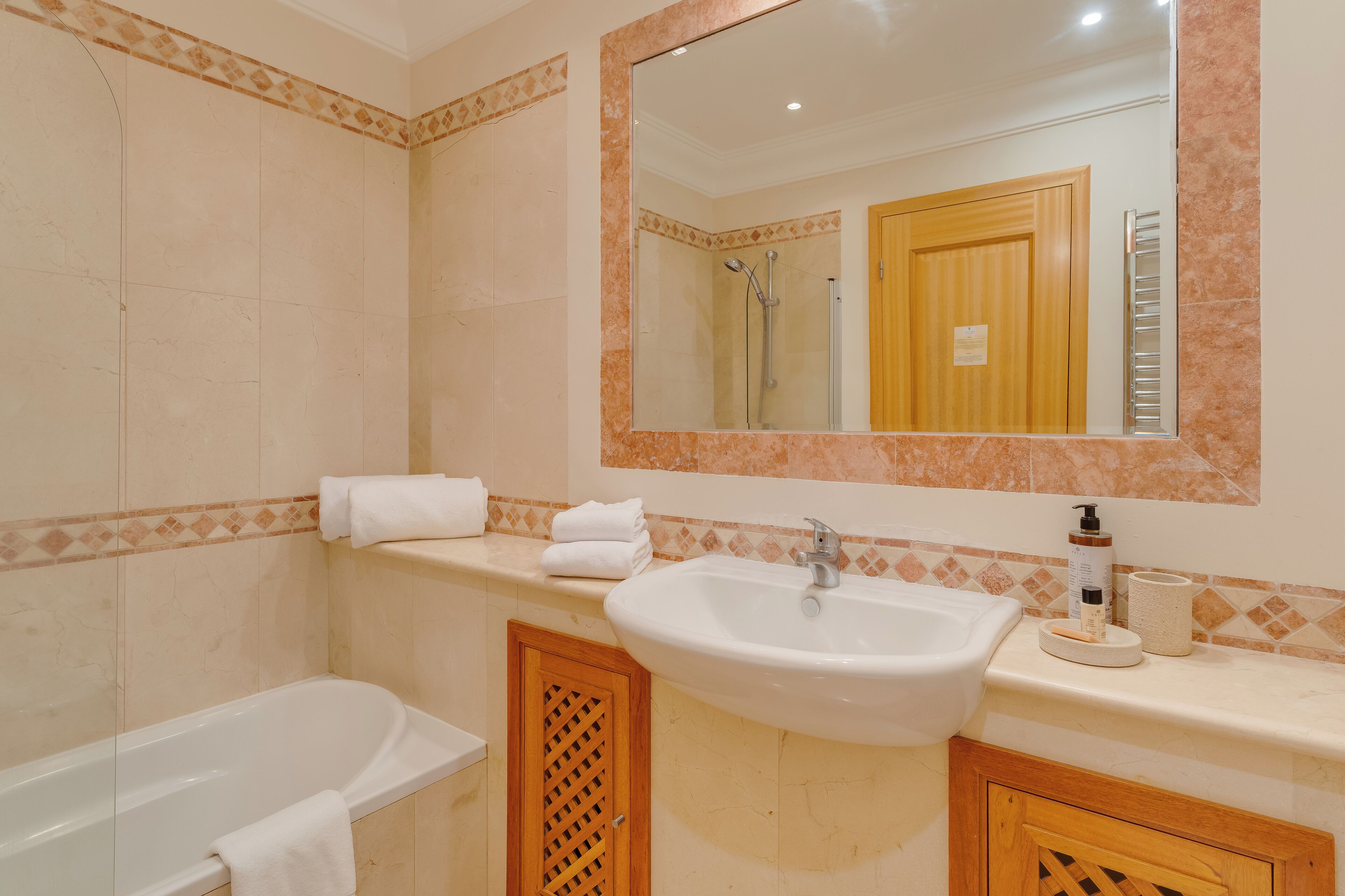 A bathroom with a bathtub, sink, and mirror.