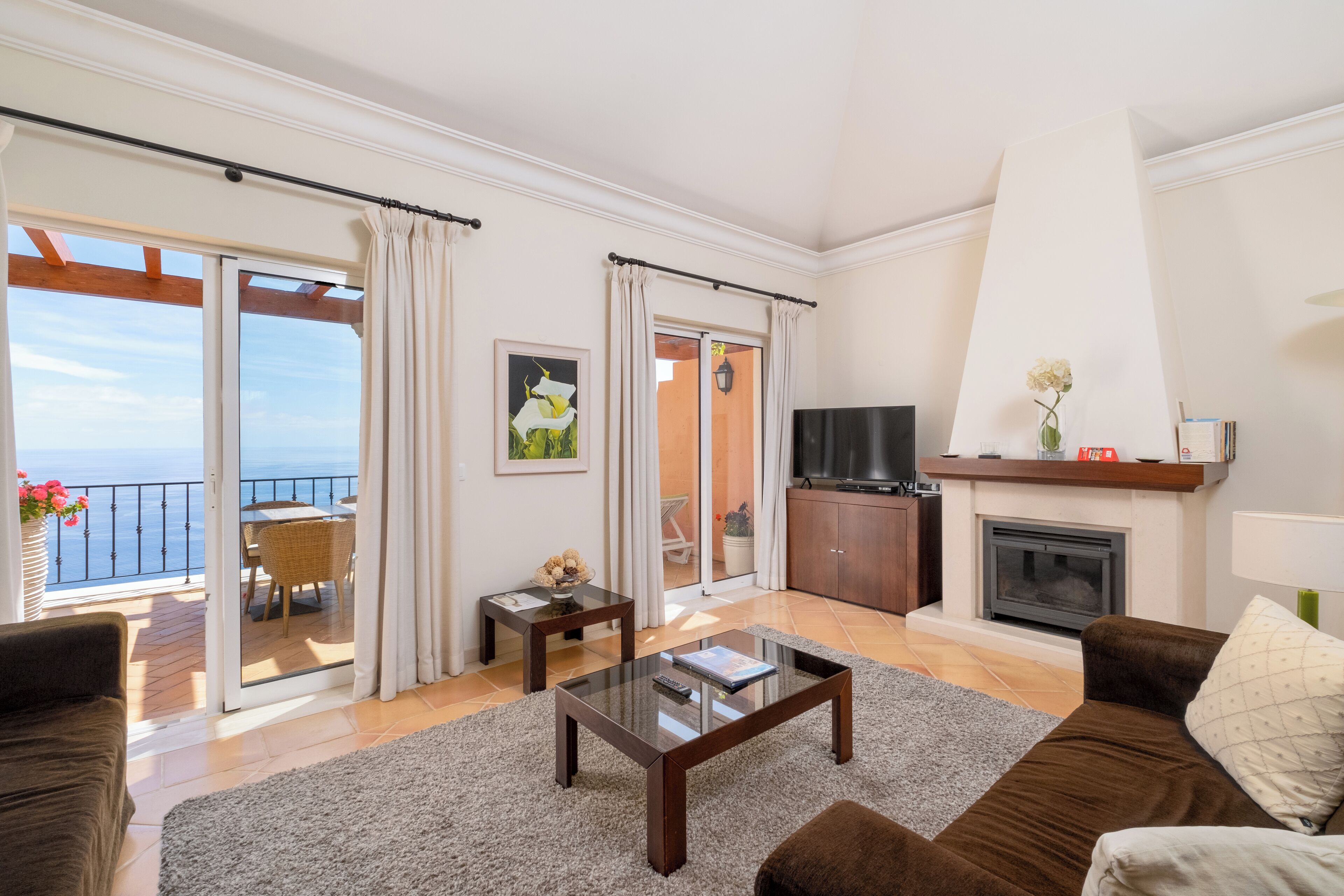 A spacious living room with a balcony, a fireplace, and a television.