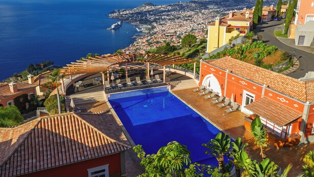 A rooftop pool with a view of the sea and a cityscape.