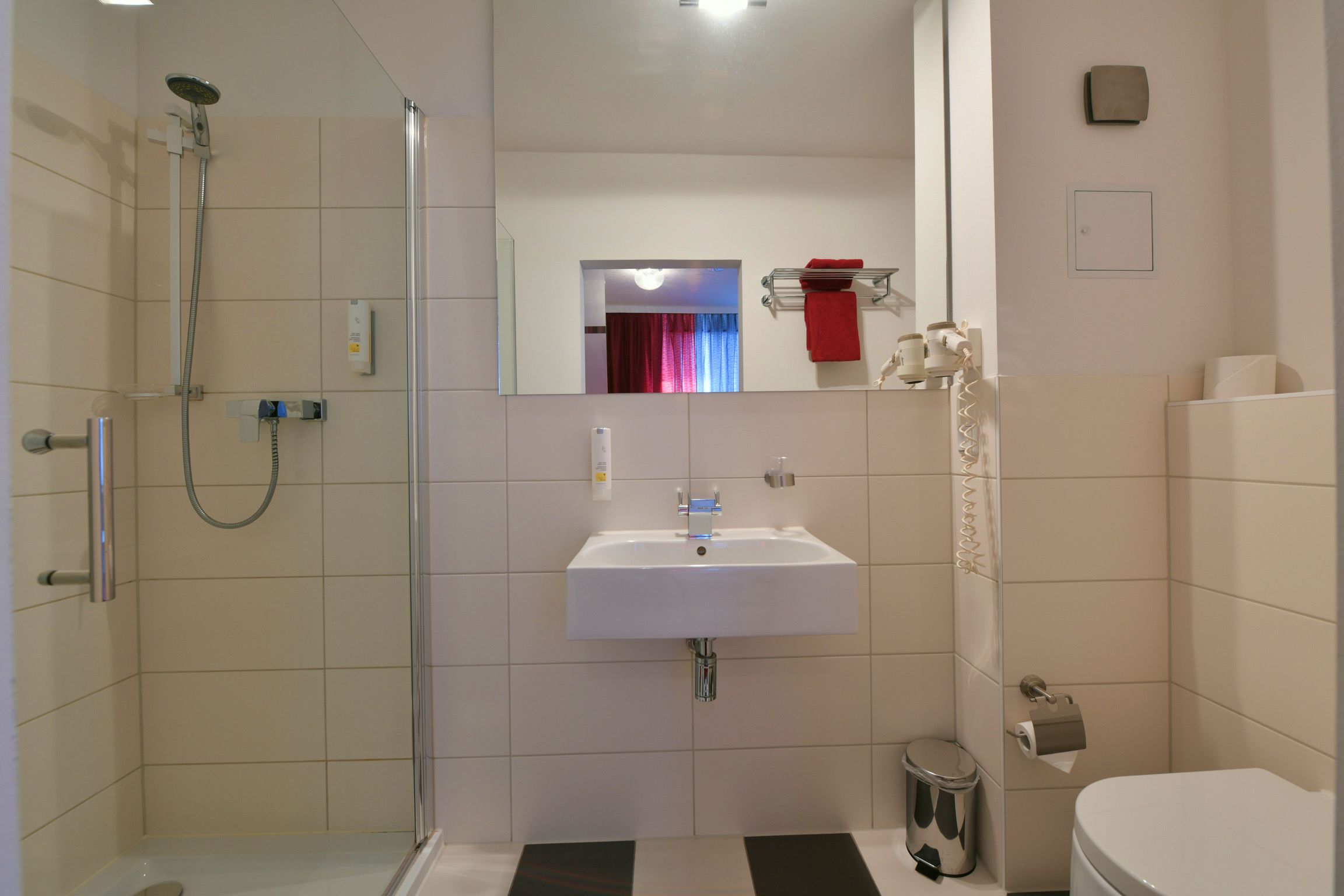 Ein modernes Badezimmer mit einer Duschkabine aus Glas, einem weißen Waschbecken und einer Toilette.