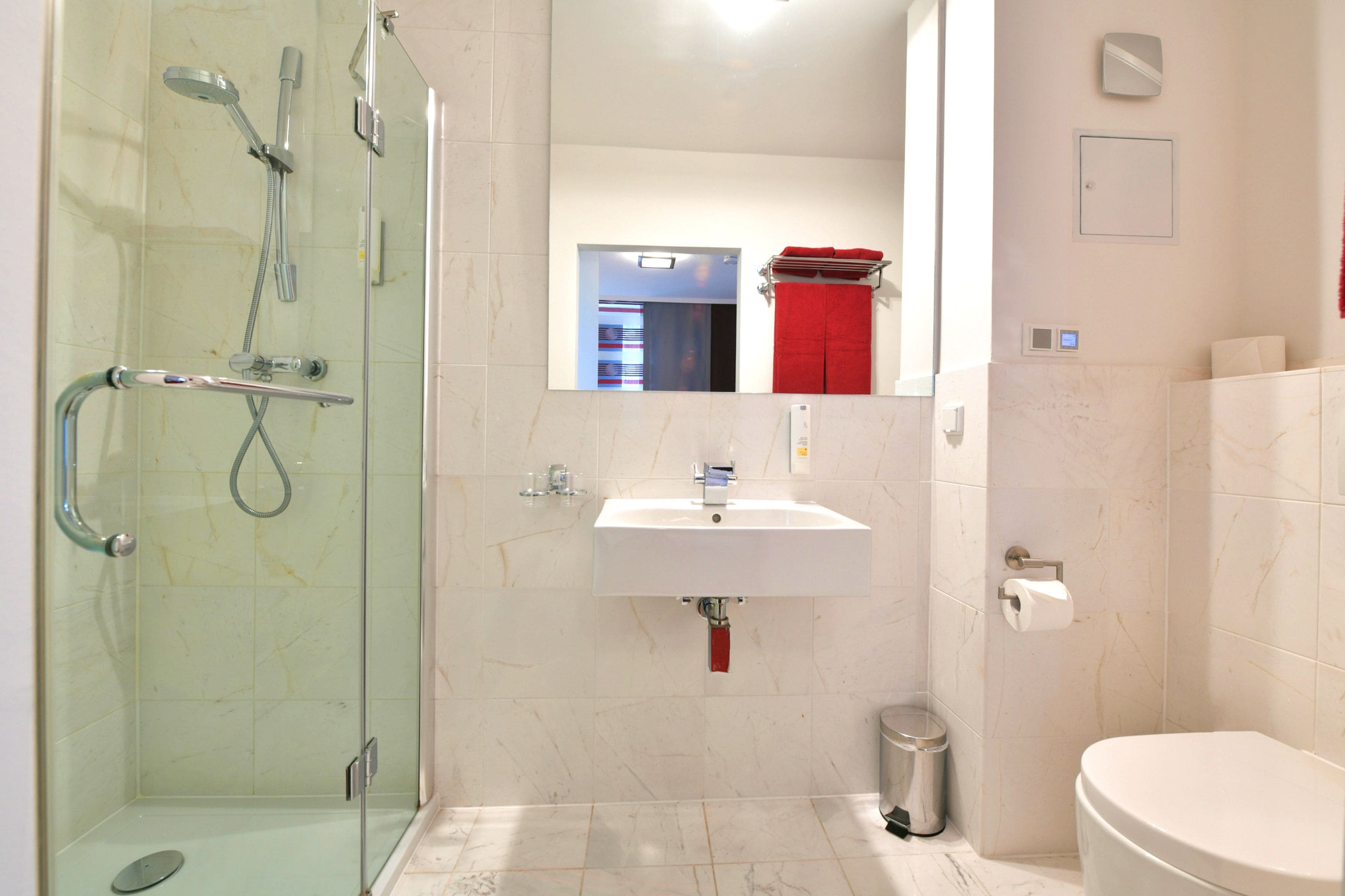 A modern bathroom with a glass-enclosed shower, a white sink, and a toilet.
