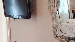 Un comedor con una mesa y sillas, un televisor montado en la pared y un espejo decorativo.
