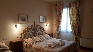Un dormitorio con una cama, dos mesitas de noche, un cabecero decorativo y dos cuadros en la pared.