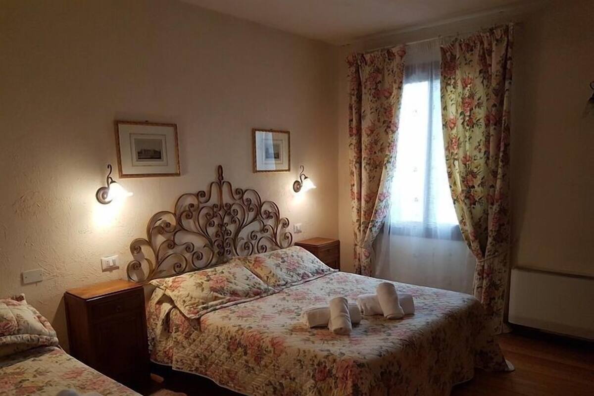 Un dormitorio con una cama, dos mesitas de noche, un cabecero decorativo y dos cuadros en la pared.
