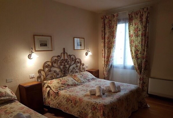 Un dormitorio con una cama, dos mesitas de noche, un cabecero decorativo y dos cuadros en la pared.