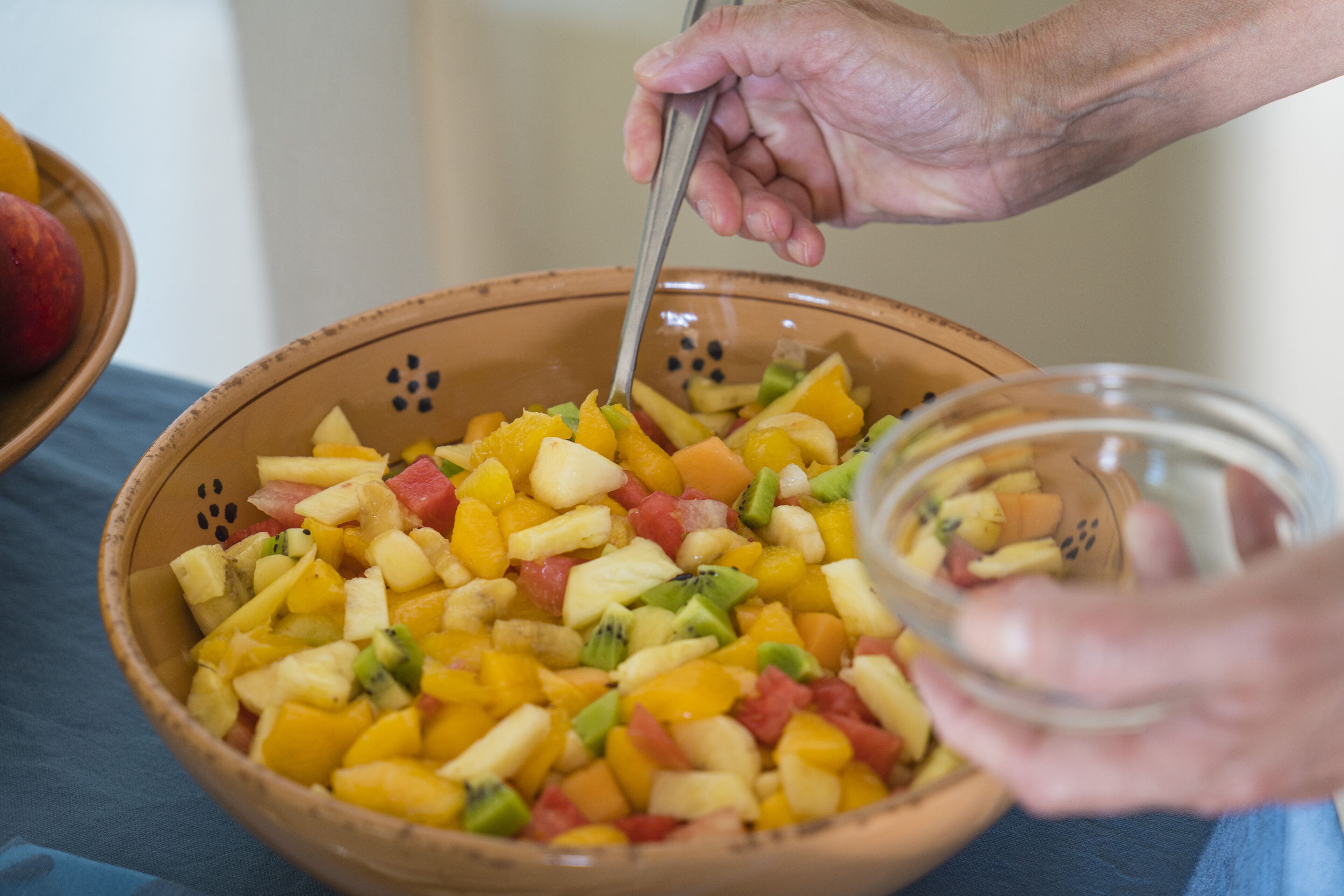 A bowl of mixed fruit salad with a spoon in it.