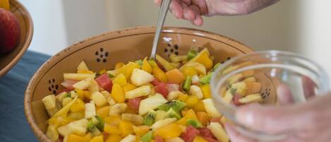 A bowl of mixed fruit salad with a spoon in it.