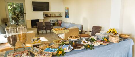 A buffet table with various food items and a television in the background.