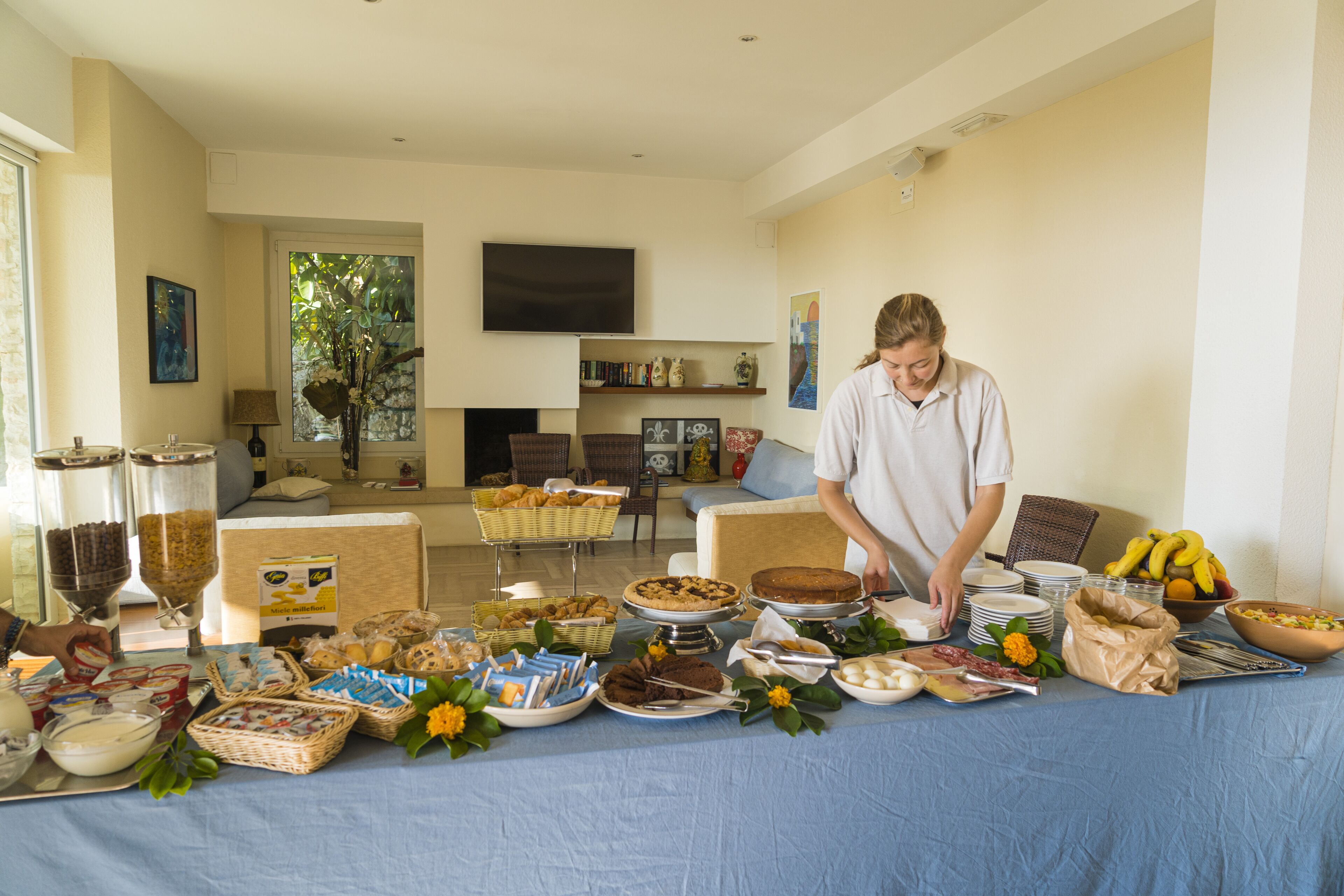 A buffet table with various food items and a person serving.