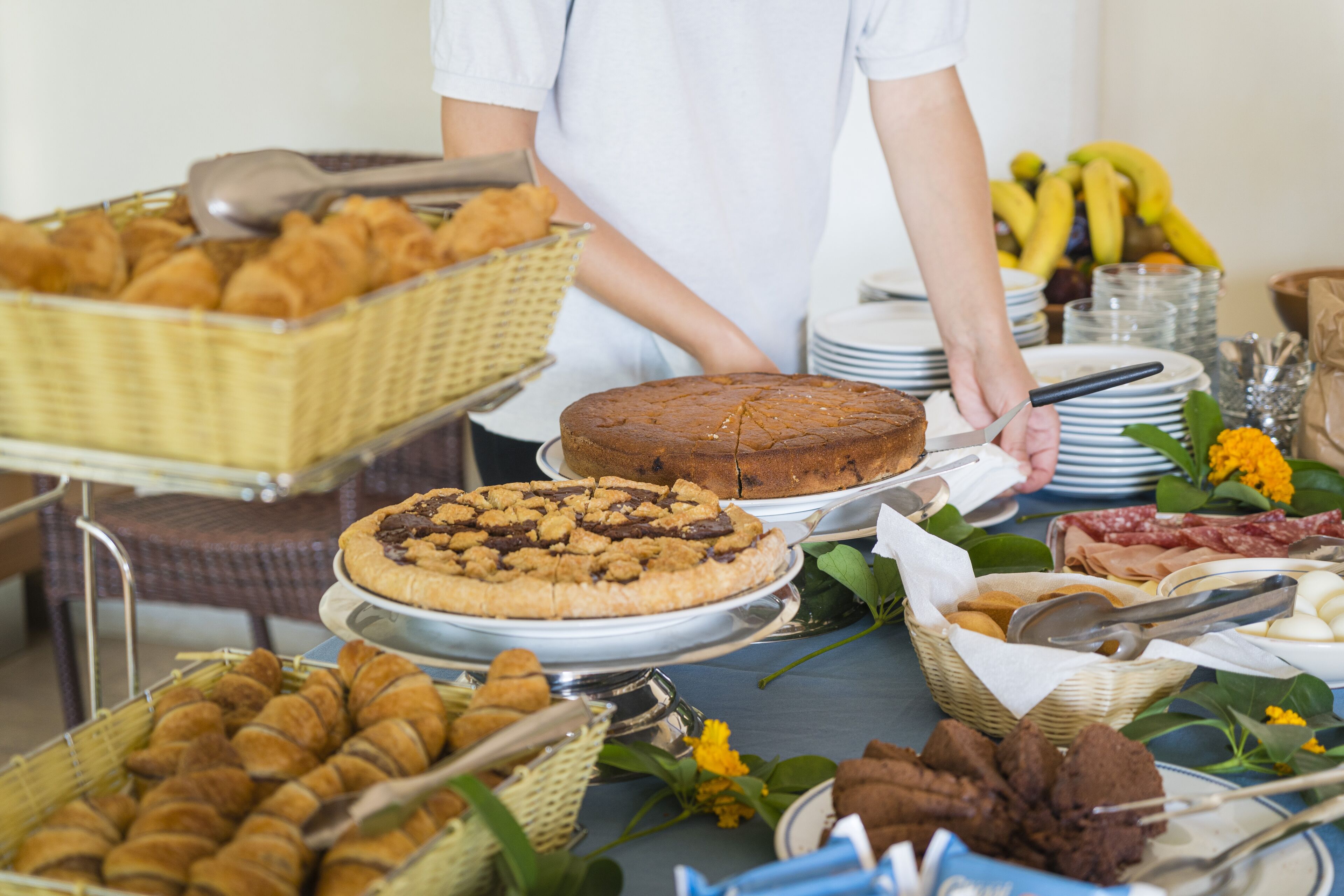Une table de buffet proposant divers plats, notamment des pâtisseries, un gâteau et un panier de fruits.