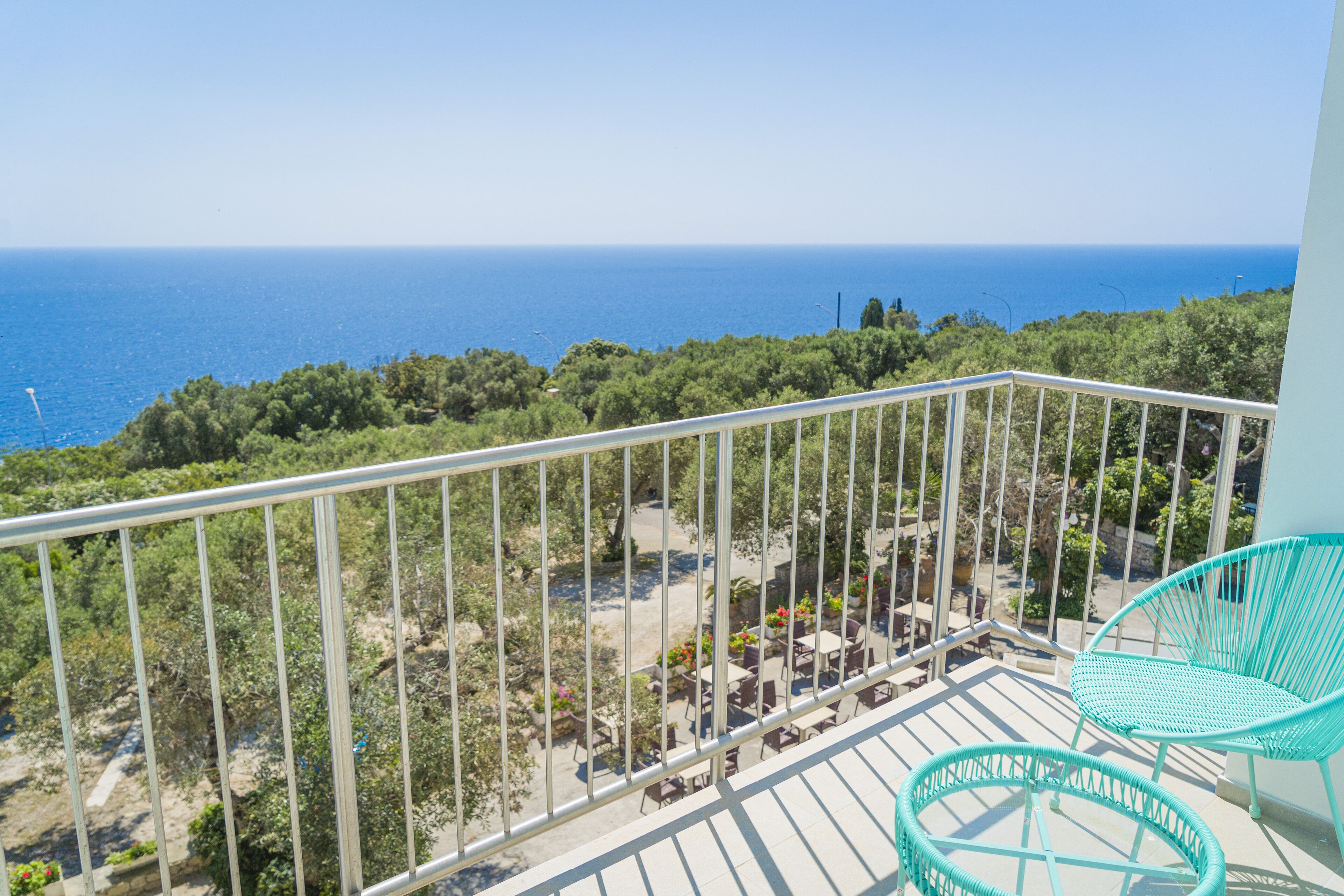 Uma varanda com vista para o mar, móveis de exterior e grade de metal.
