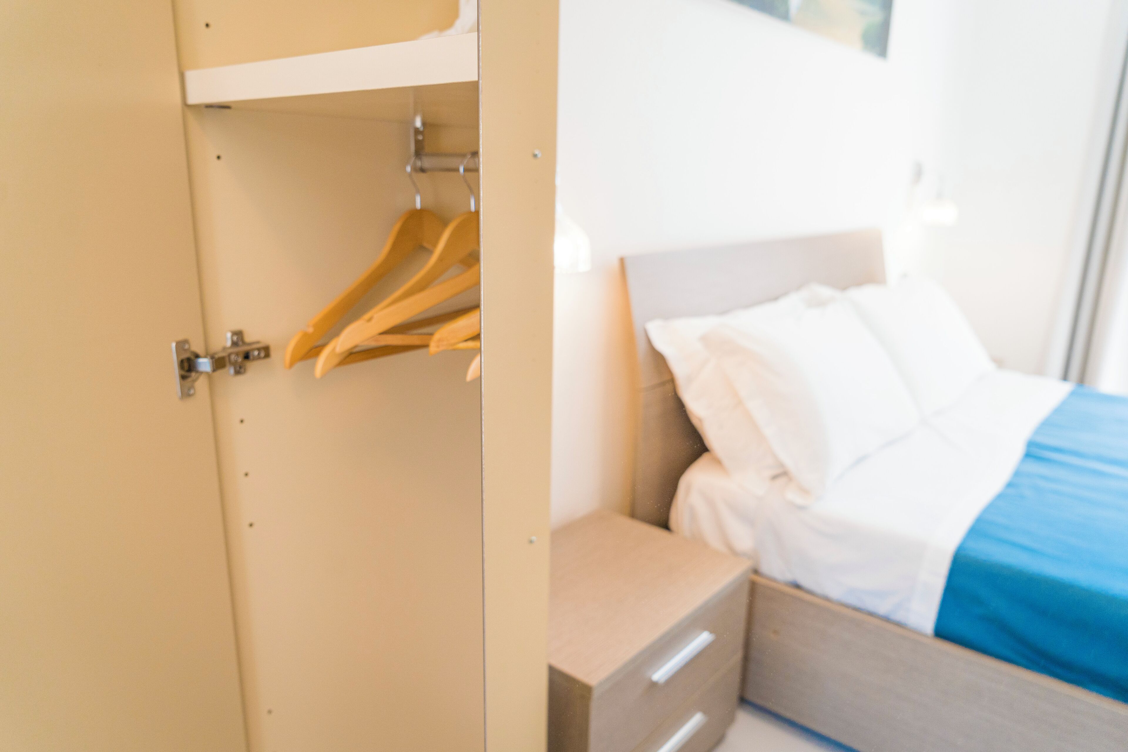 Une chambre d’hôtel comprenant un lit, une table de chevet et une armoire avec des cintres.