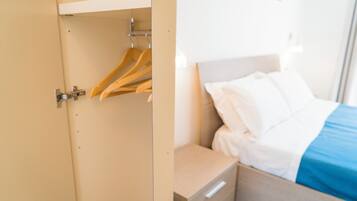 Une chambre d’hôtel comprenant un lit, une table de chevet et une armoire avec des cintres.