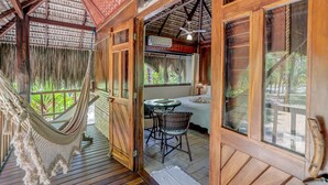 A wooden room with a hammock, a table with chairs, and a bed. - Aldeia da Mata Eco Lodge (Uruçuca)