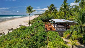 A beachside resort with a wooden deck, outdoor seating, and a view of the ocean. - Aldeia da Mata Eco Lodge (Uruçuca)
