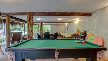 Enjoy a game of pool in this cozy room with a pool table, comfortable seating, and a view of the surrounding greenery.