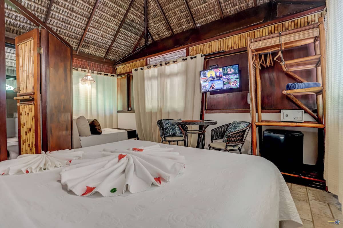 A hotel room with a large bed, a TV on the wall, a small table, and a chair.
