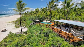 A beachside resort with a pool, wooden deck, and lounge chairs.
