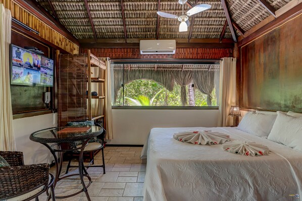 A hotel room with a bed, a TV, a table, and chairs.
