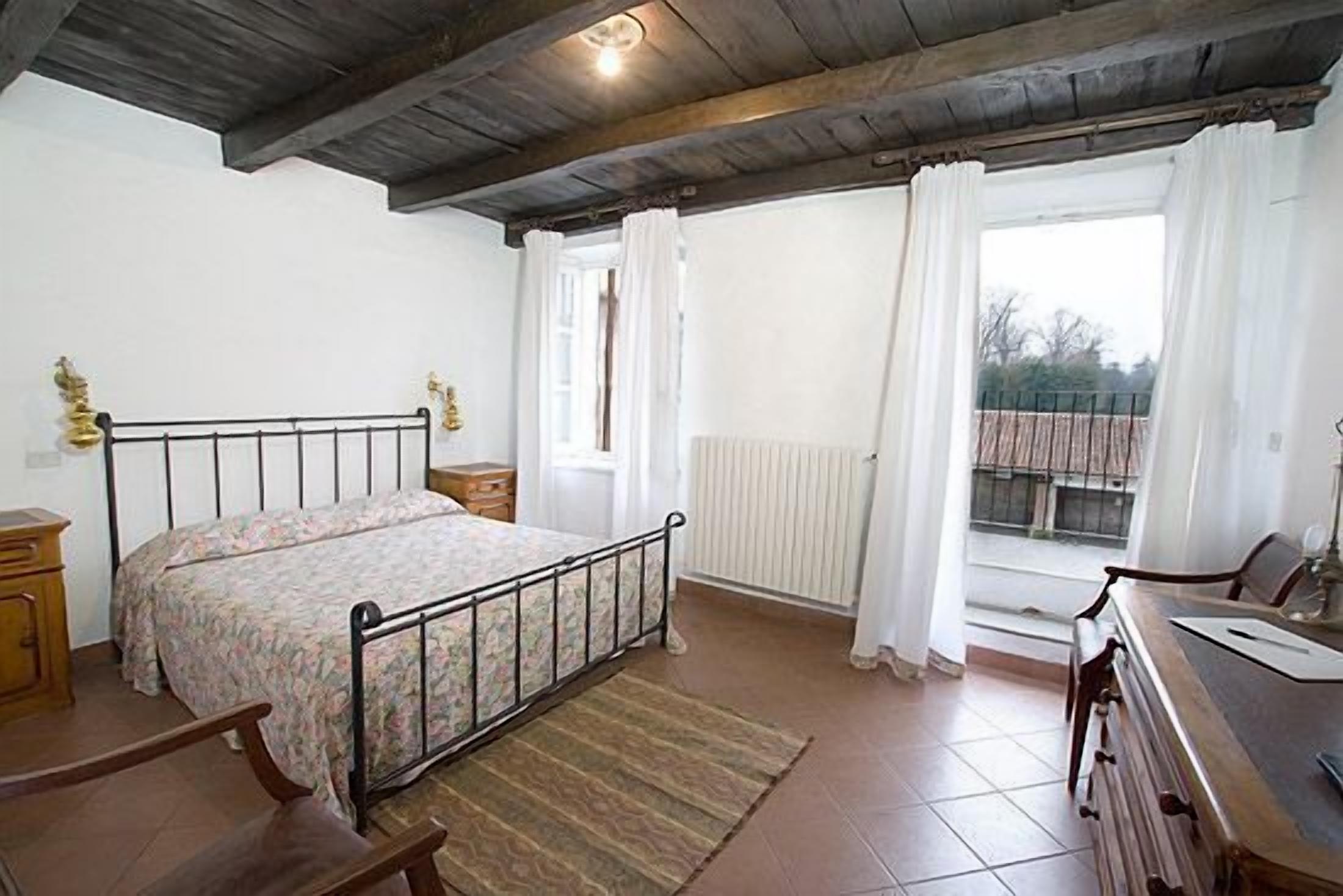A bedroom with a bed, wooden dresser, and a window with curtains.