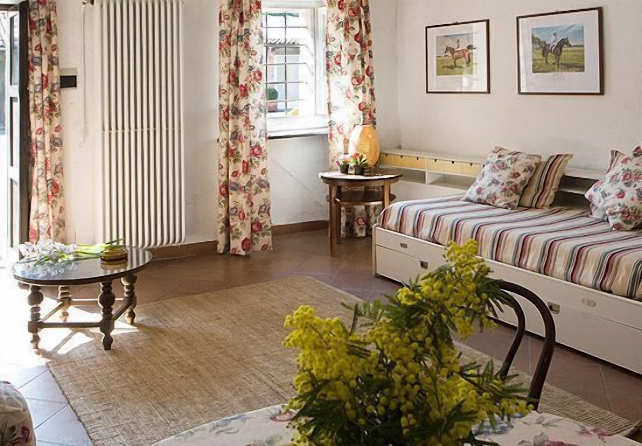 Un dormitorio acogedor con cama, mesita de noche, lámpara y ventana con cortinas.