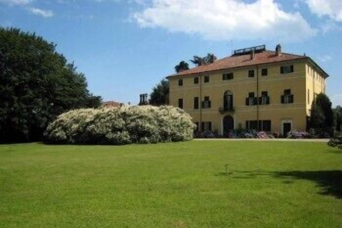 A large, yellow building with a red roof, surrounded by a well-maintained lawn and a large bush.