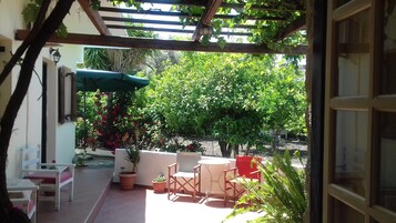 Un patio al aire libre con pérgola, asientos y plantas en macetas.