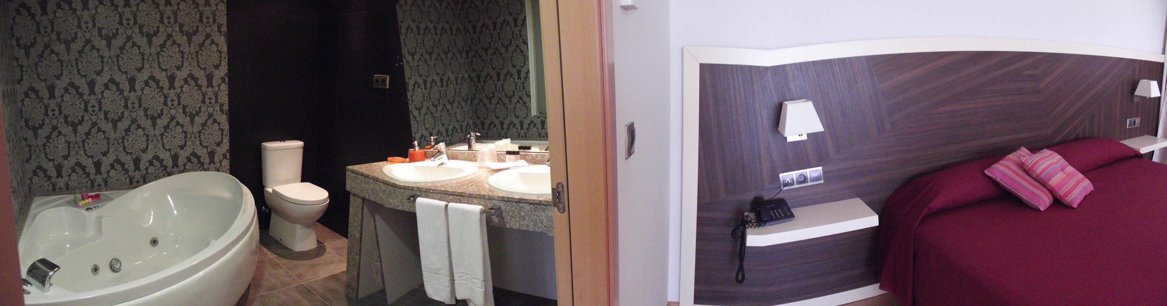 A bathroom with a bathtub, toilet, and vanity with two sinks.