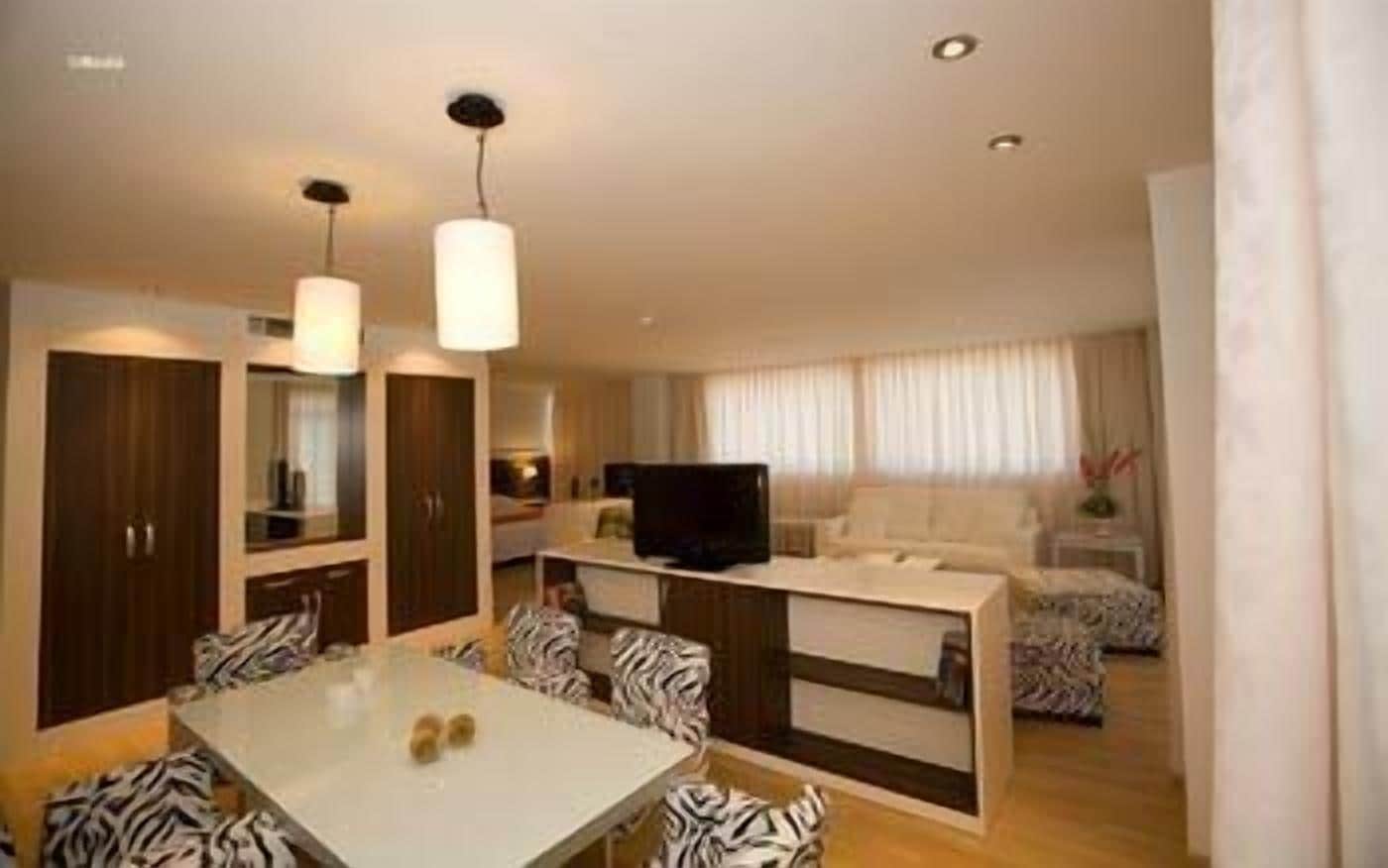 A modern hotel room with a dining area, a sofa set, and a TV.